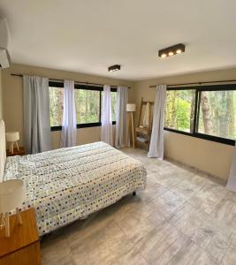 a bedroom with a bed and large windows at Bosque Libertad Loft in Mar Azul