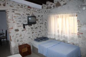 a bedroom with a bed and a tv on a stone wall at Denizkızı Sevilay Pansiyon in Ayvalık