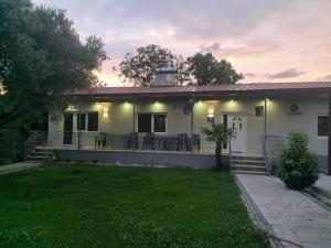 a white house with a porch and a lawn at Apartments&studio Villa Antigona in Gevgelija