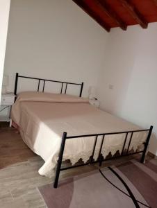 Cama en habitación blanca con marco de cama en Casa in campagna, en Monte Argentario