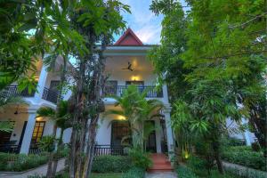a white house with trees in front of it at Sonalong Boutique Village & Resort in Siem Reap