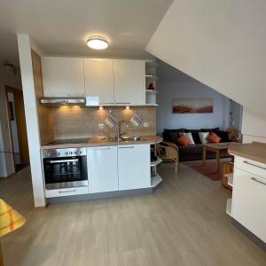 een keuken met witte kasten en een woonkamer bij Morgenröte an der See in Fehmarn