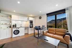 Una sala de estar con sofá y una cocina con montañas. en Lakevista Haven -- Spa Pool - Hot Tub with Views, en Queenstown
