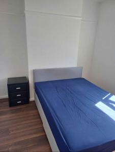 a bedroom with a blue bed and a night stand at Day time room in London