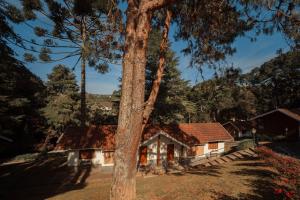 uma casa com uma árvore em frente em Pousada dos Quatis em Campos de Jordão