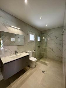 a bathroom with a toilet and a sink and a shower at Massalia Suites Villa Vita in Agios Stefanos