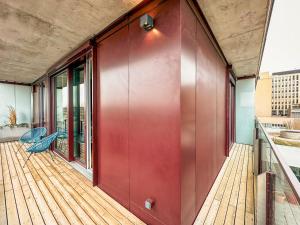 a deck with a red wall and a blue chair at KAISER LODGE - AlpenLuxus Collection in Vienna