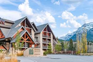 a large building with mountains in the background at Chic Rockies Getaway - Pool & Hot Tub - King Bed - BBQ! in Canmore