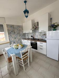 a kitchen with a table and chairs and a kitchen with white cabinets at Villa Lucia appartamento Ischia in Leporano Marina