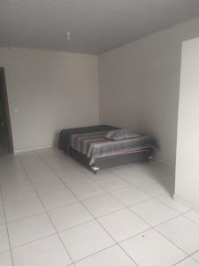 a bedroom with a bed in a white room at Pousada Martins in Teófilo Otoni