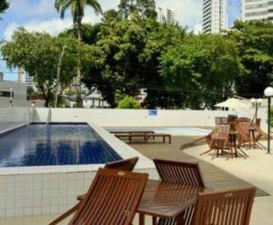 a patio with a table and chairs and a swimming pool at Flat Rosarinho Essence in Recife