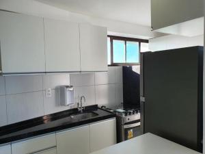 a kitchen with white cabinets and a black refrigerator at Flat Rosarinho Essence in Recife