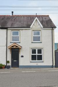 a white house with a black door on a street at No32 Carmarthen Road in Llandeilo