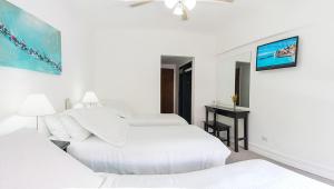 a white bedroom with two beds and a television at Hotel Corbel Superior by bund in Mar del Plata +32 photos