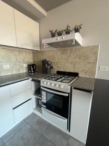 a kitchen with white cabinets and a stove top oven at Departamento Ambar PERICO in Perico