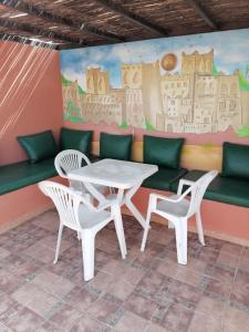 a table and chairs in front of a wall with a mural at Dar Aourir in Aourir