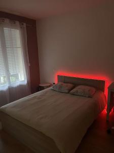 a bedroom with a bed with a red light at Appartement chaleureux Bordeaux in Villenave-dʼOrnon