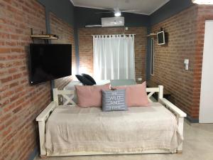 een slaapkamer met een bed met roze kussens en een flatscreen-tv bij Quinta Mi Quincho in San Pedro