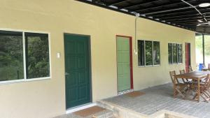 a house with green doors and a table on a patio at Woodstock Camp Chalet in Bentong