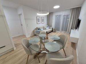 ein Wohnzimmer mit einem Glastisch und Stühlen in der Unterkunft Apartament Alicja Plażowa Park in Międzywodzie