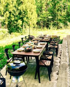 白馬村にあるSUKH Hakuba by Jade Groupの椅子とボウルと皿が置かれた長い木製のテーブル