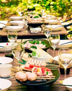 白馬村にあるSUKH Hakuba by Jade Groupの食べ物の皿とワインのグラスが置かれたテーブル