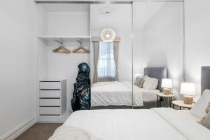 a white bedroom with a bed and a couch at Portside by Property Mums in Melbourne