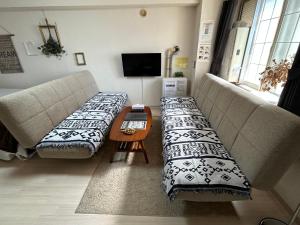 a living room with two couches and a table at アンブローシア平岸 in Toyohira