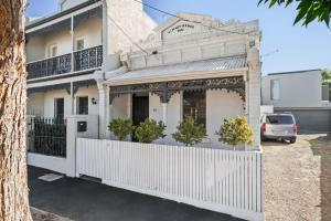 a white house with a white fence in front of it at Portside by Property Mums in Melbourne