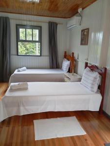 two white beds in a room with a window at Pousada 4 Estações in Louro Müller