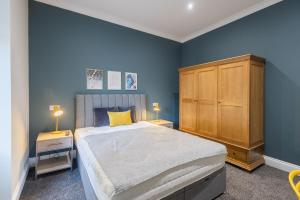 una camera da letto blu con un letto grande e un armadio in legno di 3BR Gem West End Walk to Glasgow Uni Parking a Glasgow
