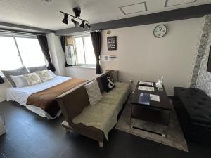 a bedroom with a bed and a couch and a clock at アンブローシア平岸 in Toyohira