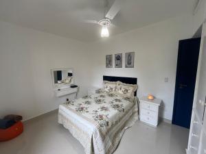 ein weißes Schlafzimmer mit einem Bett und einem Fernseher in der Unterkunft Ap 700m Praia Enseada-TV Smart, Garagem-Elevador in Guarujá + 6 Fotos