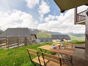 einen Holztisch und Stühle auf einer Terrasse mit Bergblick in der Unterkunft Studio cosy pour 4 près des pistes à Peyragudes - FR-1-695-76 in Gouaux-de-Larboust