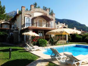 a house with a swimming pool with chairs and umbrellas at Villa Xanthos 301 in Oludeniz