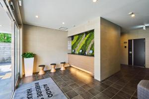 a lobby with stools and a wall with a painting at ALFACIO RIVERSIDE STAY HAKATA in Fukuoka