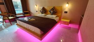 a bedroom with a bed with pink lights on the floor at The Days in Devaprayāg