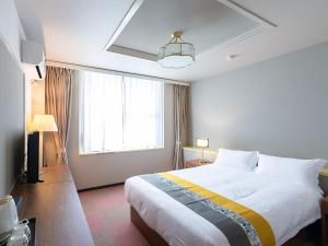 um quarto com uma grande cama branca e uma janela em ホテルオアシスガーデン em Obita