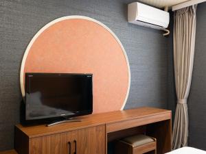Um espelho em um quarto de hotel com uma televisão sobre a mesa. em ホテルオアシスガーデン em Obita