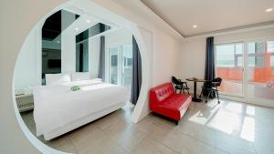 a bedroom with a white bed and a red chair at Geoje Wave Hotel & Pension in Geoje