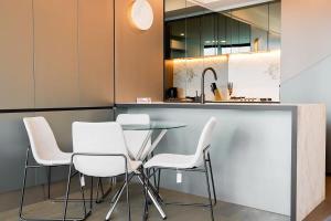 a kitchen with a glass table and white chairs at Premier Tower - Modern CBD Apt 45th Floor home in Melbourne