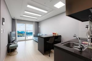 a kitchen with a sink and a living room at Yeosu Stay and Park in Yeosu
