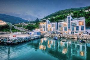 a large building next to a river with boats in it at Aramer Spa Pension in Yeosu