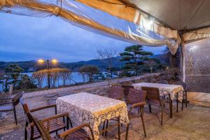 a patio with tables and chairs and a view of the water at Gapyeong Pension Aqua Vita Spa Pension in Gapyeong