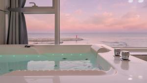 a bath tub with a view of the ocean at Gangneung Pension G7 Spa Pension in Gangneung