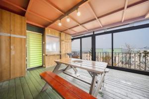 a wooden deck with a bench and a table at Yeosu Flower Day Ocean View Spa Couple Family Pension in Yeosu