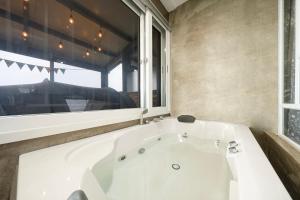 a white bath tub in a bathroom with a window at Yeosu Flower Day Ocean View Spa Couple Family Pension in Yeosu +6 photos