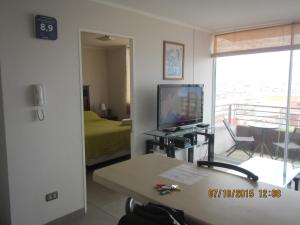 Sala de estar con TV, cama y mesa en Departamentos Parque Costanera, en Antofagasta