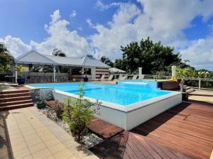 een zwembad op een houten terras met een houten terras bij Gîte Hibiscus piscine partagée in Saint-François +39 foto's