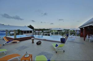 een patio met een zwembad en stoelen en een huis bij Gîte Hibiscus piscine partagée in Saint-François